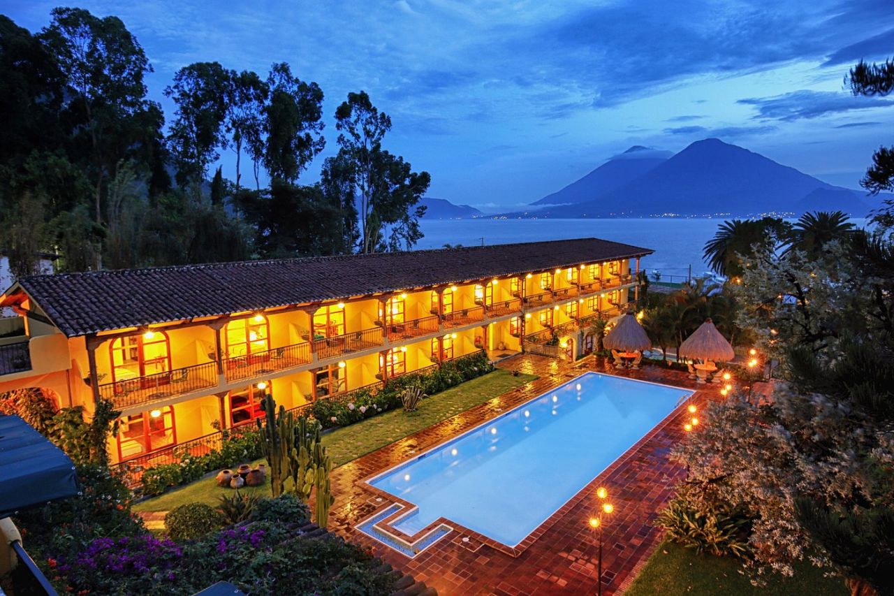 Pool and hotel with palm trees and a lake in the distance